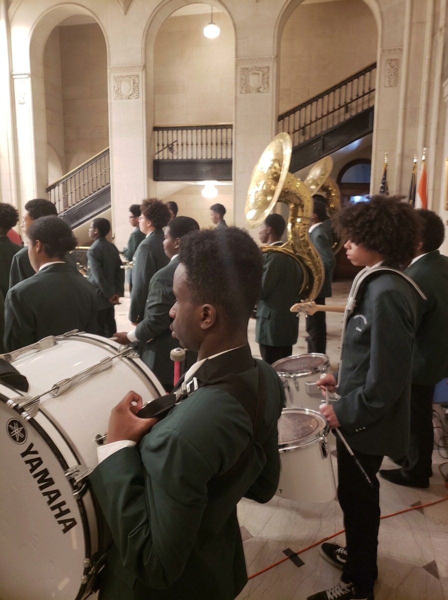 Green Tech Charter School drum line members with bass and snare drums preparing to perform at a community event in Albany, NY