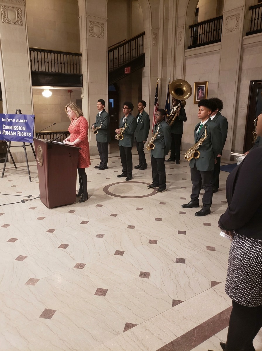 Green Tech Charter School band members standing in uniform with saxophones and sousaphone during a City of Albany ceremony