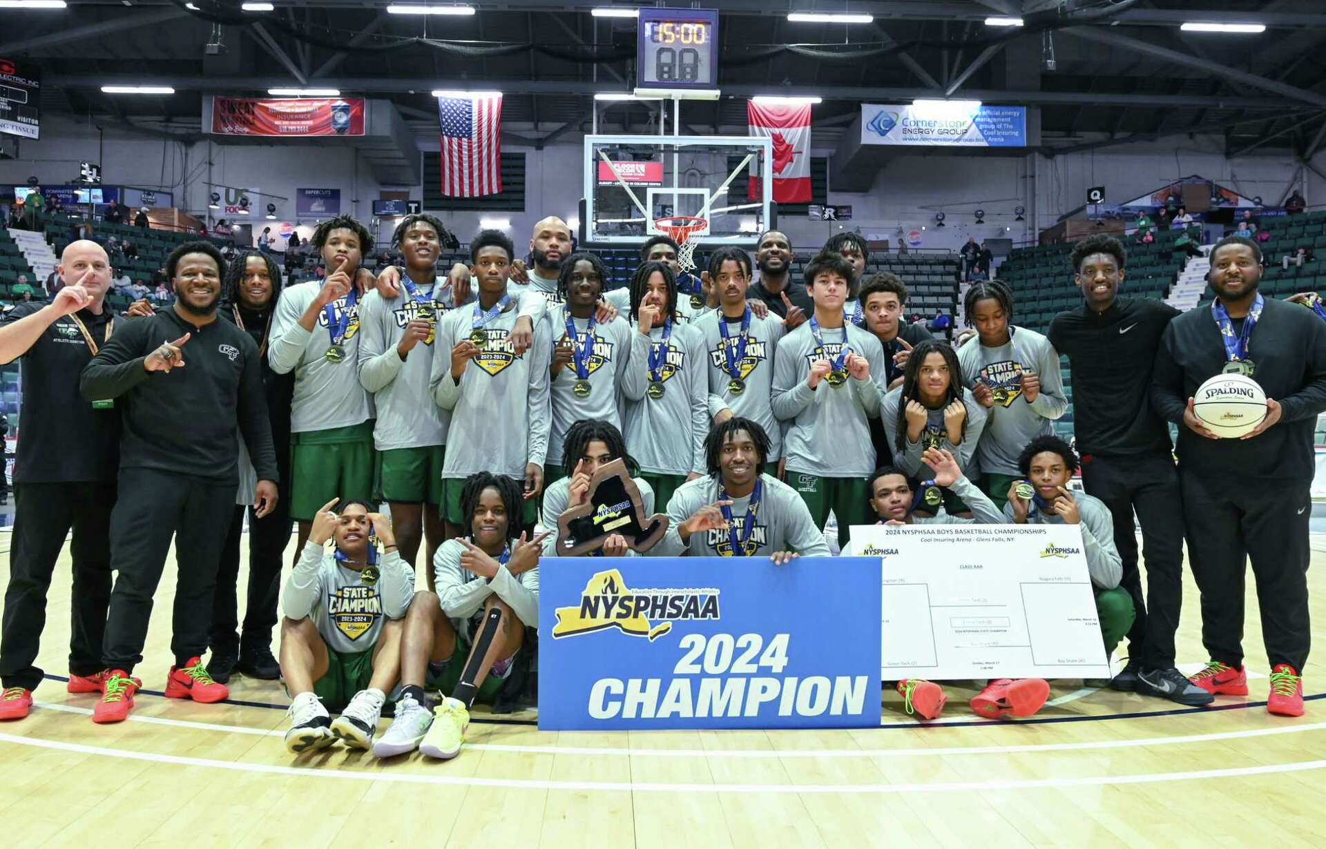 Green Tech Charter School Eagles basketball team celebrating with the 2024 NYSPHSAA Champion banner and state championship medals